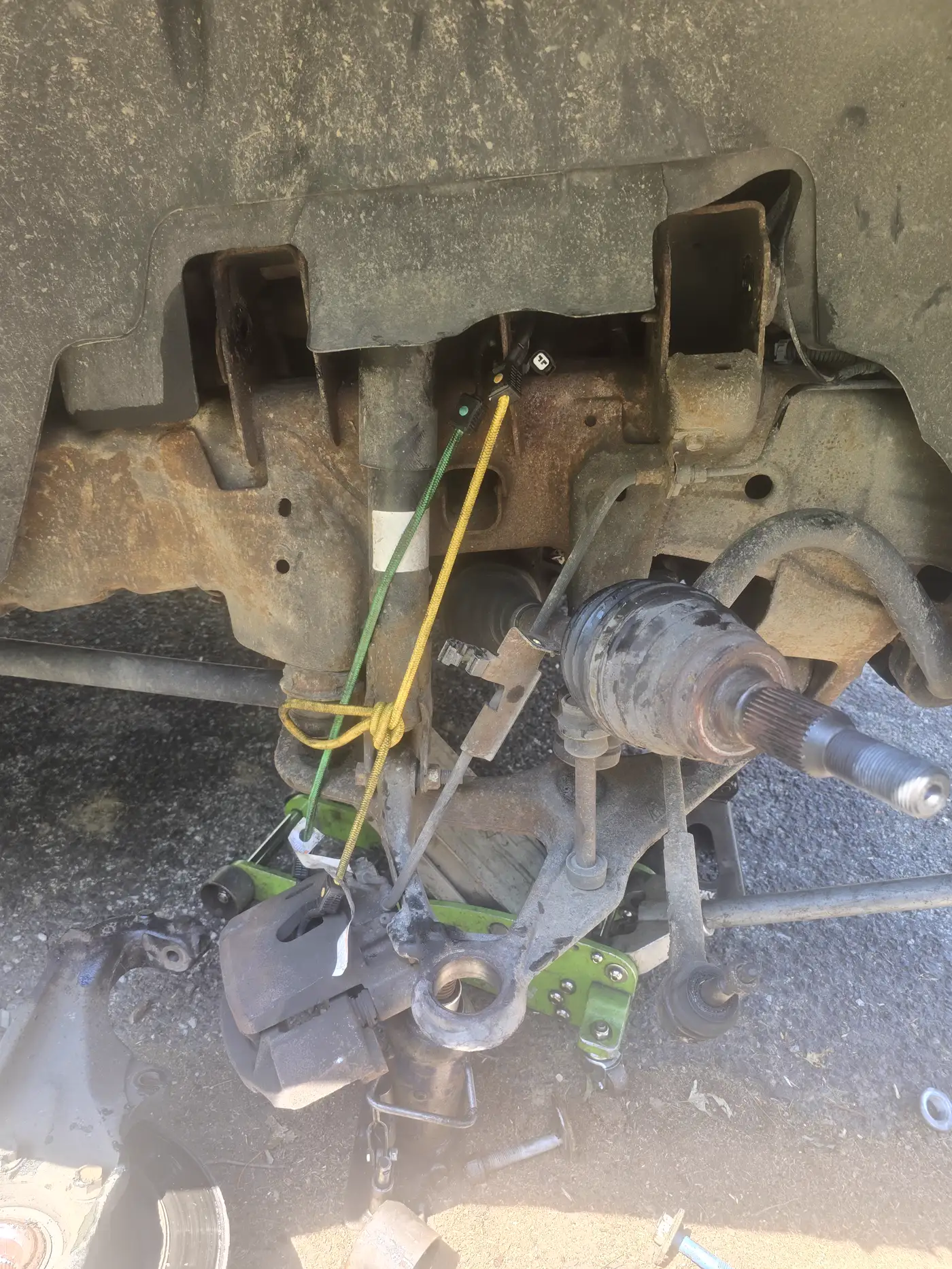 Subframe, CV axle, and suspension parts laid out during a repair